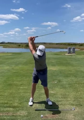 golfer swinging a golf club at the top of the back swing position