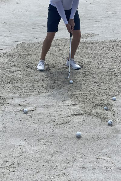 golfer with feet dug in sand bunker about to hit a bunker shot